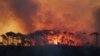 FILE - A helicopter water bombs a fire in the Tokai Forest, March 2, 2015, near Cape Town, South Africa. An new report warns that climate change could increase the number of wildfires by 50% by 2100.