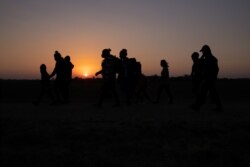 The sun rises as asylum-seeking migrant families from Honduras and El Salvador walk towards the border wall after crossing the Rio Grande River into the United States from Mexico on a raft, in Penitas, Texas.