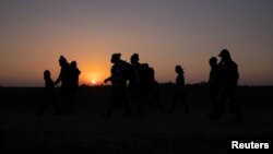 ARCHIVO - Empieza a amanecer mientras familias migrantes, provenientes de Honduras y El Salvador y que buscan asilo en Estados Unidos, caminan hacia el muro fronterizo tras cruzar el Río Grande, en Peñitas, Texas, el 26 de marzo de 2021.