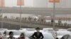 People wearing face masks walk past cars clogged with heavy traffic on a road as Beijing is hit by polluted air and sandstorm, May 4, 2017. Authorities in Beijing issued a blue alert on air pollution as sandstorm swept through the Chinese capital city on 