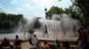 People cool off under a fountain along the Canal de l'Ourcq in Paris, France.