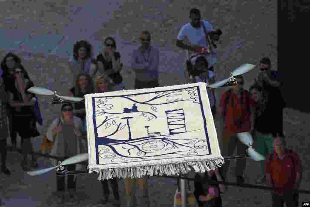People watch the "Flying Carpet", an artwork created by French artist Moussa Sarr, as it takes off from the Saint Jean fort in Marseille, southern France. It's part of "L'artiste dans la cite" ('The Artist in the City') events organized by the MUCEM, "Musée des Civilisations de l'Europe et la Méditerranée."