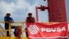 ARCHIVO - Trabajadores frente a una plataforma de perforación en un pozo petrolero operado por la petrolera estatal venezolana PDVSA, en Morichal. 