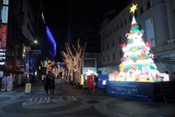 Personas con mascarilla caminan por una zona comercial mayormente vacía en Seúl, Corea del Sur, el sábado 5 de diciembre de 2020. Seúl ordenó estrictas medidas de distanciamiento ante el aumento de casos de COVID-19 por segundo día consecutivo.