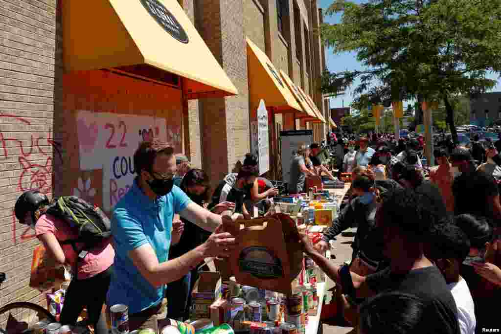 Personas en un punto de donaci&#243;n de alimentos cerca del &#225;rea que se quem&#243; durante las protestas contra la muerte en la custodia policial de George Floyd en Minneapolis,