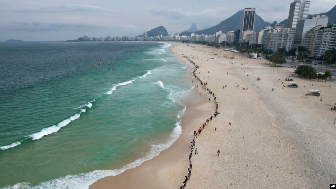 FILE - People create a line along Copacabana beach for a symbolic group hug with the sea on World Oceans Day in Rio de Janeiro, Brazil, June 8, 2022.