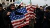 FILE - Protesters deface an American flag during an anti-U.S. rally over the U.S. airstrike in Iraq that killed Iranian Revolutionary Guard Gen. Qassem Soleimani, in Tehran, Iran, Jan. 3, 2020.