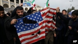 FILE - Protesters deface an American flag during an anti-U.S. rally over the U.S. airstrike in Iraq that killed Iranian Revolutionary Guard Gen. Qassem Soleimani, in Tehran, Iran, Jan. 3, 2020.