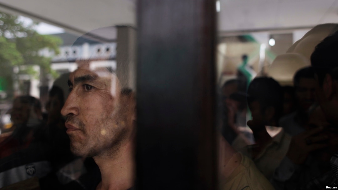 FILE - An ethnic Hazara man looks out from behind a glass panel at a temporary shelter in Karawang, Indonesia's West Java province.