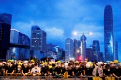 FILE - Anti-extradition bill protesters stand behind a barricade during a demonstration near a flag-raising ceremony marking the anniversary of Hong Kong's handover to China, in Hong Kong, July 1, 2019.