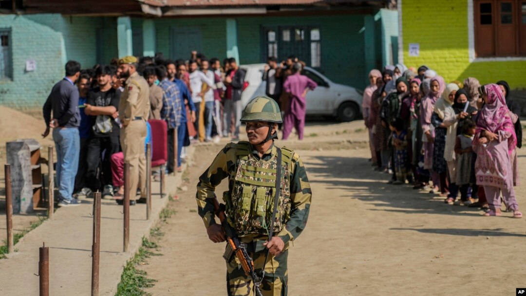 An Indian soldier stands guard as people wait to cast votes at a polling booth in Shadipora, India-administered Kashmir, on May 20, 2024. As the nation holds its national elections, India is cited as an example of the sharp curtailing of freedom of expression around the world.