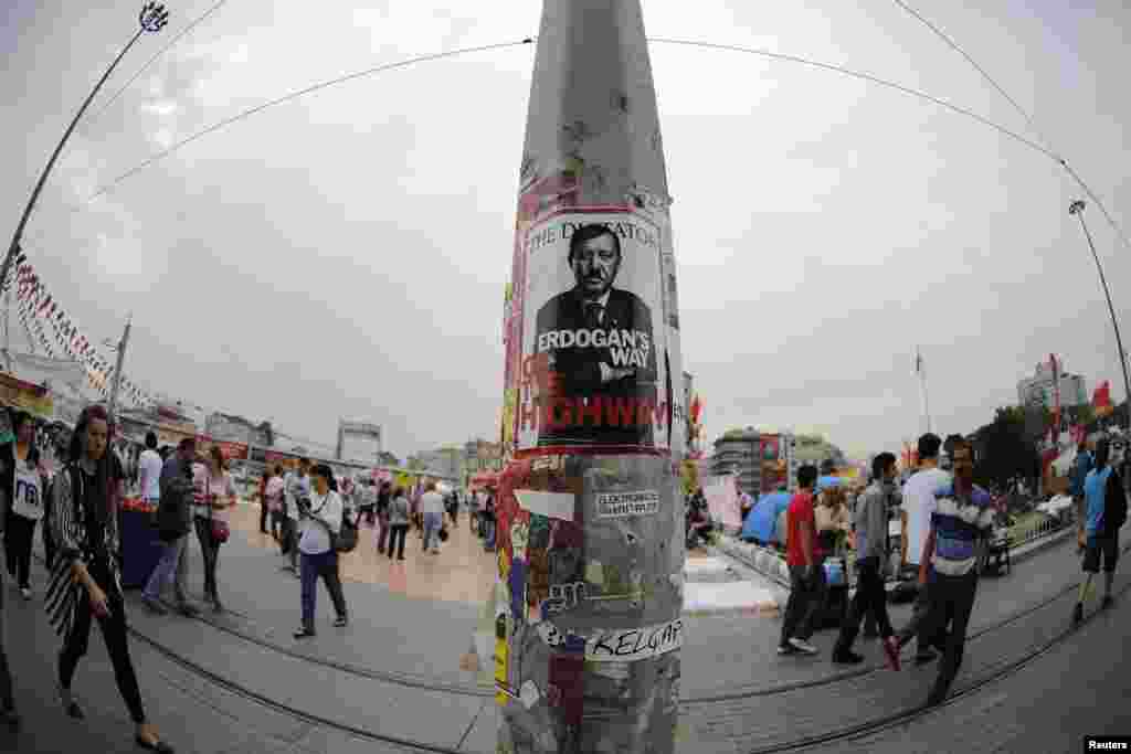 People walk past a poster depicting Turkish Prime Minister Tayyip Erdogan, put up by demonstrators, at Taksim Square in Istanbul. Erdogan flew back to a Turkey rocked by days of anti-government unrest on Friday and declared before a sea of flag-waving supporters at Istanbul airport: "These protests must end immediately."