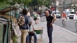 Paris book sellers near the Seine River chat as they wait for customers. (Lisa Bryant/VOA)