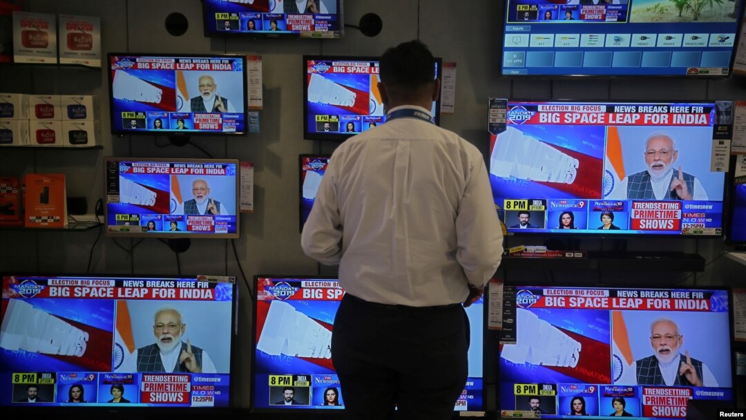 A salesman watches Prime Minister Narendra Modi addressing to the nation, on TV screens inside a showroom in Mumbai, India, March 27, 2019. 
