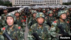 Armed paramilitary policemen stand in formation during a gathering to mobilize security operations in Urumqi, Xinjiang Uighur Autonomous Region, June 29, 2013.