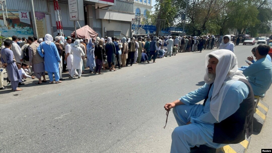 FILE - Afghans line up outside a bank to take out their money after Taliban takeover in Kabul, Afghanistan, Sept. 1, 2021. 