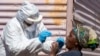 FILE - A woman opens her mouth so that a health worker can collect a sample for coronavirus testing at Lenasia South, south Johannesburg, South Africa, April 21, 2020.