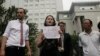 FILE - Li Wenzu, center, wife of imprisoned lawyer Wang Quanzhang, holds a paper that reads "Release Liu Ermin" as she and supporters of a prominent Chinese human rights lawyer and activists stage a protest outside the Tianjin No. 2 Intermediate People's Court in Tianjin, Aug. 1, 2016. 