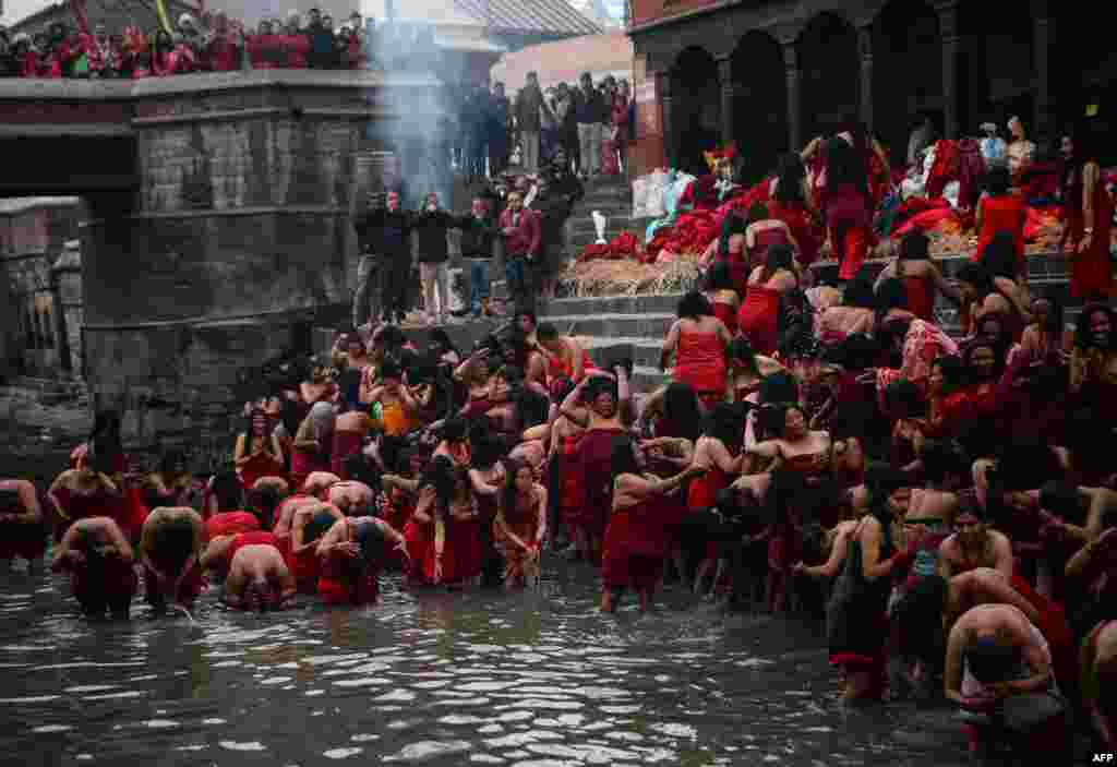 Nepali Hindu devotees perform a ceremonial bath in the holy Bagmati River at the Pashupatinath Temple during the month-long Swasthani festival in Kathmandu, Feb. 4, 2019.