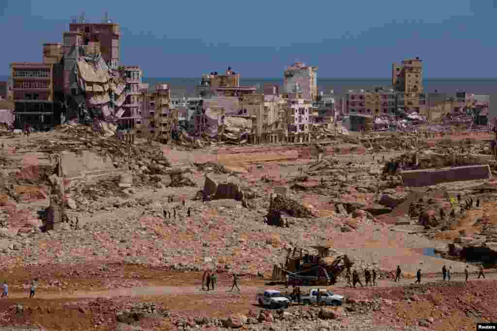 Imagem mostra pessoas a inspecionar as áreas danificadas, no rescaldo das inundações em Derna, na Líbia, a 14 de setembro de 2023.