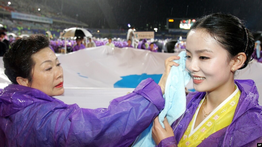 지난 2006년 6월 한국 광주 월드컵경기장에서 열린 6.15 공동선언 기념 남북공동행사에서 한국 참가자(왼쪽)가 북한에서 온 참가자의 얼굴에 묻은 빗물을 닦아주고 있다.