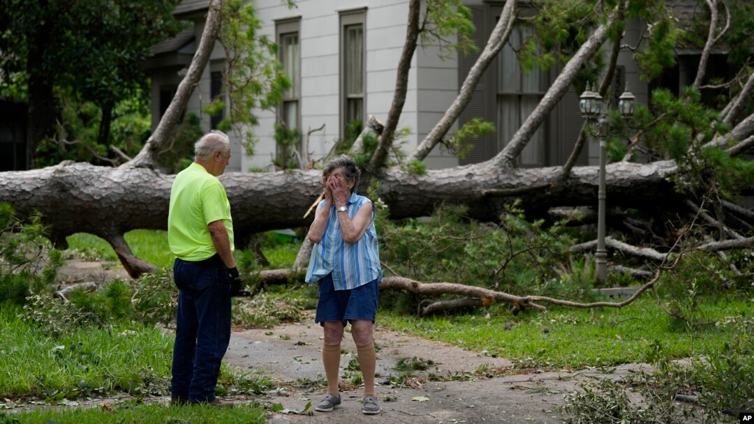 Jackie Jecmenek, a la derecha, habla con Bobby Head, un trabajador de la ciudad, frente a la casa de su vecino tras el paso de Beryl, el lunes 8 de julio de 2024, en Bay City, Texas.