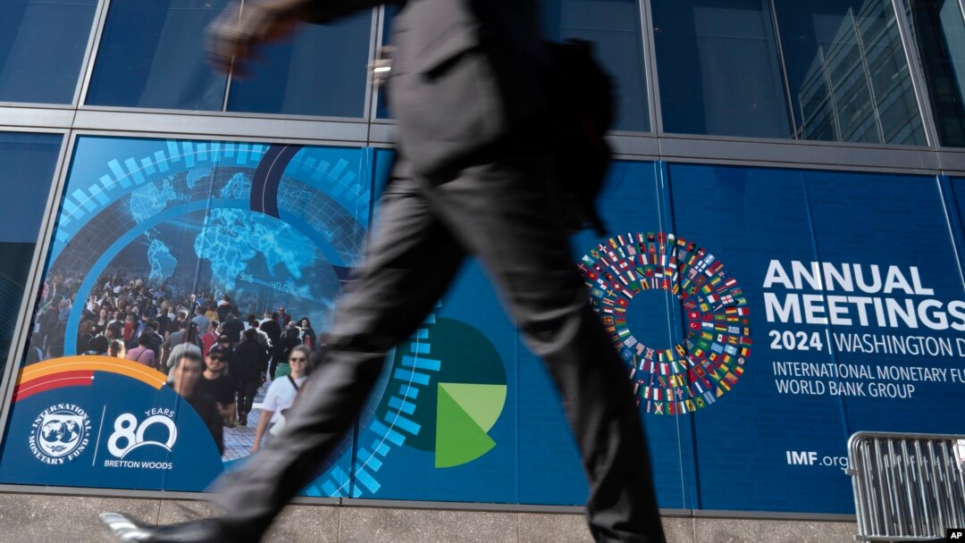 A delegate walks by an IMF banner, during the World Bank/IMF Annual Meetings at the International Monetary Fund (IMF) headquarters in Washington, Oct. 21, 2024. 