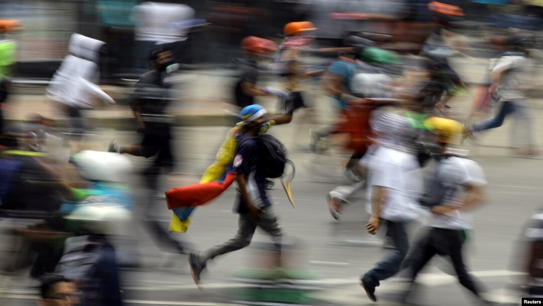 FILE - Demonstrators run during clashes with riot security forces at a protest against Venezuelan President Nicolas Maduro's government in Caracas, Venezuela, May 30, 2017. 