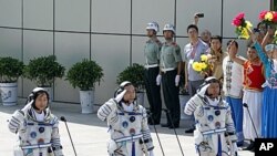 China's astronauts salute before they depart for the Shenzhou 9 spacecraft rocket launch pad at the Jiuquan Satellite Launch Center in Jiuquan, China, June 16, 2012 (AP).
