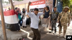 A man dances as women sing national songs in front of a polling station during the second day of the presidential in Cairo, Egypt, Tuesday, March 27, 2018.