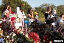 FILE - Well-wishers place mementos the day students and parents arrive for voluntary campus orientation at the Marjory Stoneman Douglas High School, for the reopening, following the mass shooting in Parkland, Florida, Feb. 25, 2018.