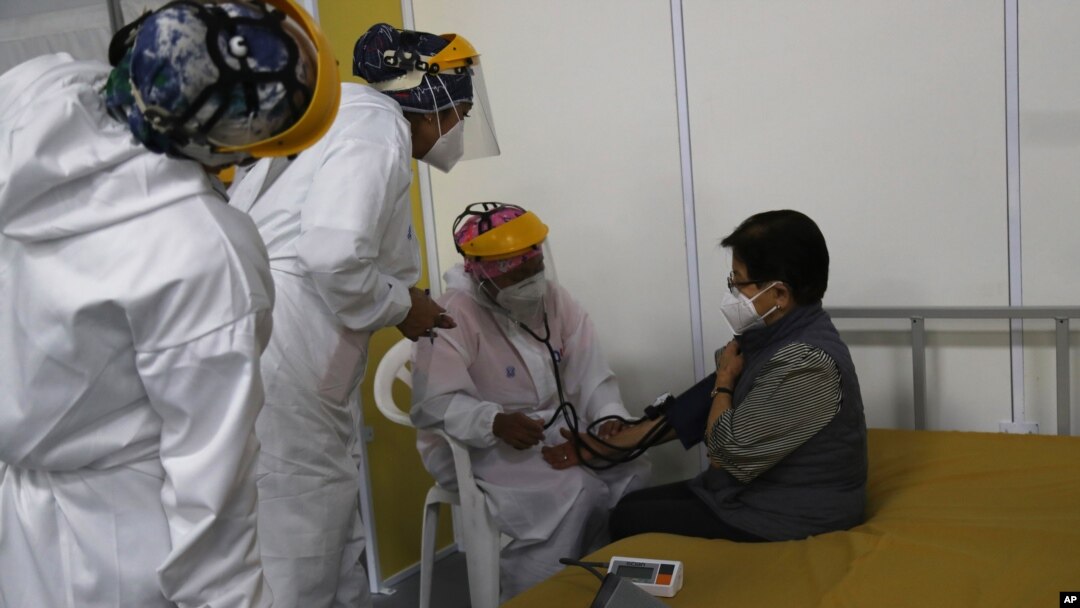 Un médico revisa los signos vitales de una anciana luego de ser inoculada con una dosis de la vacuna Pfizer COVID-19 como parte del período de observación, en el centro de convenciones convertido en sitio de vacunación, en Quito, Ecuador, el 31 de marzo. 