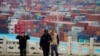 FILE - Security guards walk in front of containers at the Yangshan Deep Water Port in Shanghai, China, April 24, 2018. The U.S. will impose tariffs Friday on $34 billion worth of Chinese imports.