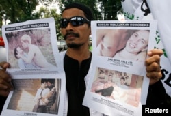 FILE - A member of the Islamic Defenders Front (FPI) holds up posters protesting films screened at the Q! Film Festival in Jakarta, Sep. 28, 2010.