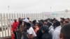 FILE - Migrants, many from Cameroon, listen to names being called for those who can claim asylum in the United States, in Tijuana, Mexico, July 28, 2019.