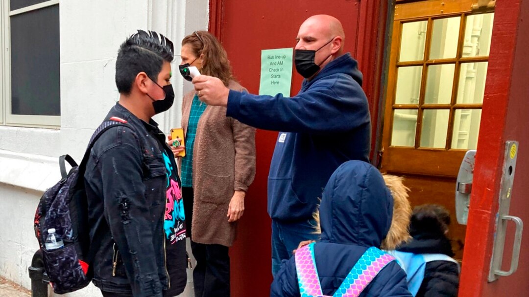 John Marro, the dean of students at the American Sign Language and English Lower School, in New York, takes students' temperatures as they arrive Jan. 3, 2022.