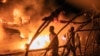 FILE - People walk by U.N. vehicles which were set on fire, in Goma, Democratic Republic of Congo, Nov. 1, 2022. 