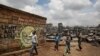 FILE - Children walk past graffiti depicting a representation of the coronavirus and warning people to sanitize to prevent its spread, in the Mathare slum of Nairobi, Kenya, April 22, 2020.
