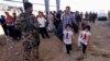 A Kurdish policeman stands guard while refugees from Mosul head to the self-ruled northern Kurdish region in Irbil, Iraq, 350 kilometers (217 miles) north of Baghdad, June 10, 2014.