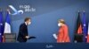 German Chancellor Angela Merkel, right, and French President Emmanuel Macron prepare to address a media conference at the end of an EU summit in Brussels, July 21, 2020. 