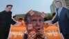 A protester wearing a mask of U.S. President Donald Trump performs with cut-out photos of North Korean leader Kim Jong Un and South Korean President Moon Jae-in, right, during a rally in Seoul, South Korea, May 25, 2018. 