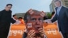 A protester wearing a mask of U.S. President Donald Trump, center, performs with cut-out photos of North Korean leader Kim Jong Un and South Korean President Moon Jae-in, right, during a rally against the United States' policies against North Korea near the U.S. embassy in Seoul, South Korea, May 25, 2018. The signs read "Apology." 