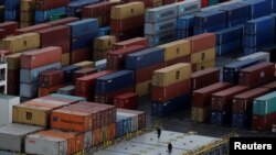 FILE - Workers stand on the deck of a container vessel as it is unloaded at a container terminal in Liverpool, northern England, Dec. 9, 2016.