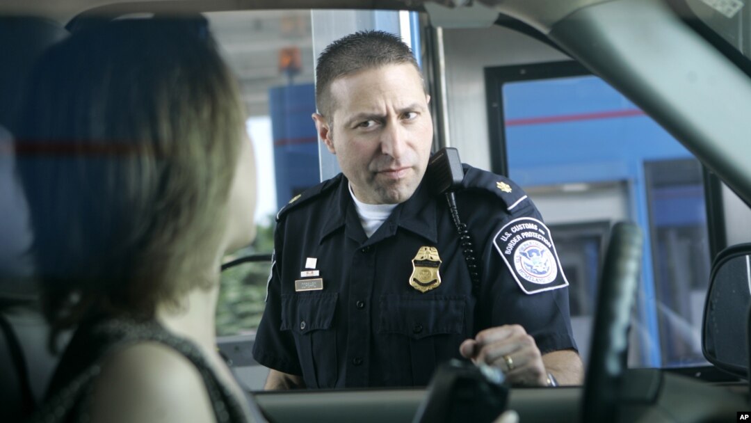 FILE - U.S. Customs and Border Protection officer Kevin Corsaro speaks with an unidentified motorist entering the United States from Canada at the border in Buffalo, N.Y.