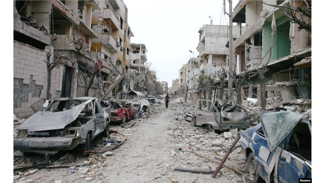 The damaged cars and buildings are seen in the besieged town of Douma, Eastern Ghouta, Damascus, Feb. 25, 2018.