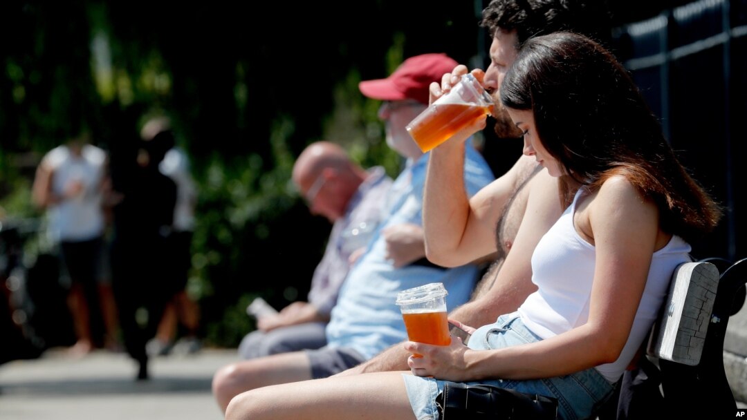 People sit in front of a pub that sells take-out drinks, in London, Britain, June 23, 2020. 