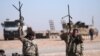 FILE - Syrian Democratic Forces fighters hold up their weapons in the north of Raqqa city, Syria, Feb. 3, 2017.