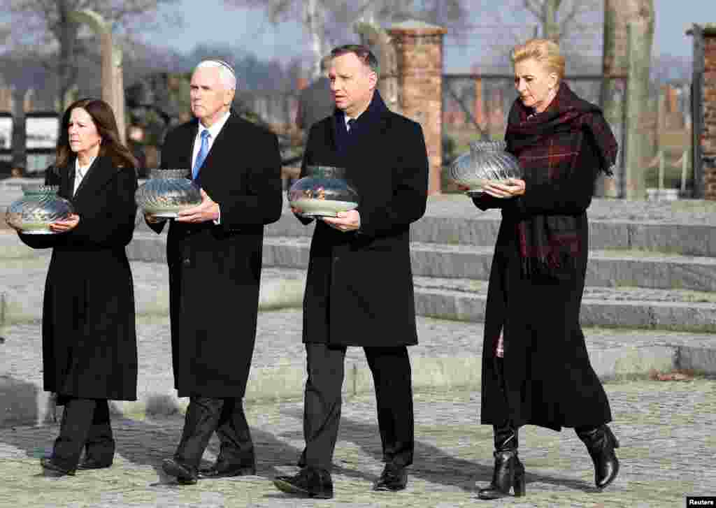 U.S. Vice President Mike Pence with his wife Karen and Poland&#39;s President Andrzej Duda with first lady Agata Kornhauser-Duda carry candles at the Monument to the Victims at the former Nazi German concentration and extermination camp Auschwitz II-Birkenau, near Oswiecim, Poland.