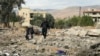 A man and two children walk above debris at the site of an overnight Israeli airstrike in the eastern Lebanese village of al-Qasr, on Nov. 11, 2024. 