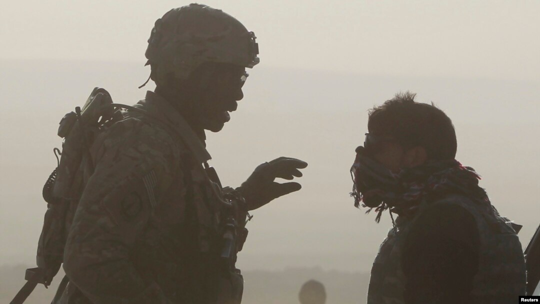 FILE - A U.S. soldier and a translator are silhouetted as they talk to each other at a joint U.S. military and Afghan police checkpoint in Nangarhar province, eastern Afghanistan, March 7, 2012. 